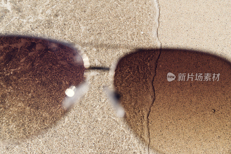 POV透过太阳镜破波在Pedn Vounder海滩的海岸线，康沃尔在一个阳光明媚的九月的一天。